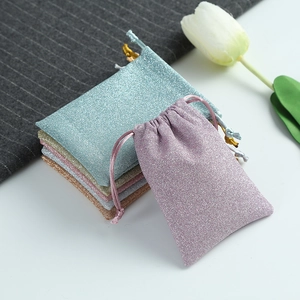 Detail of glitter drawstring jewelry pouches in purple, teal, gold, and beige colors