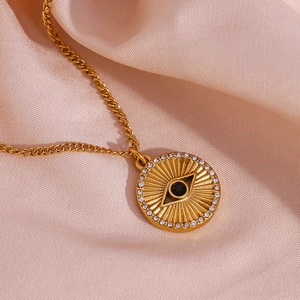 Detail shot of a 18K gold-plated sunburst coin necklace with evil eye and white zircons