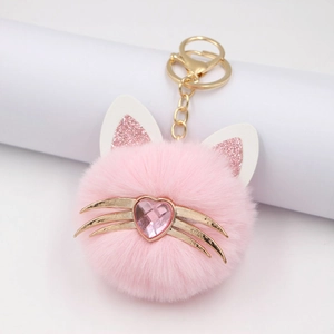 Pink plush cat head keychain with gold whiskers and heart jewel on a clean background