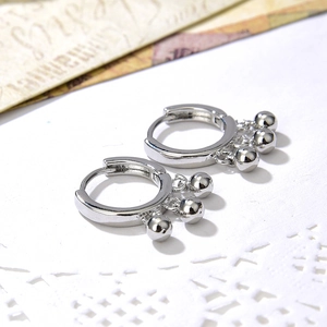 Silver hoop earrings featuring three polished metal beads on a vintage lace background