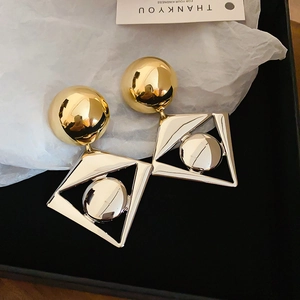 Detailed view of geometric contrast earrings with gold spheres and silver metal frames