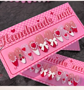 Detail of handmade almond press-on nails with 3D bows, pearls, and cherry motifs in size M