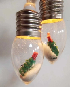 Macro shot of LED Christmas bulb featuring a miniature tree and snow inside