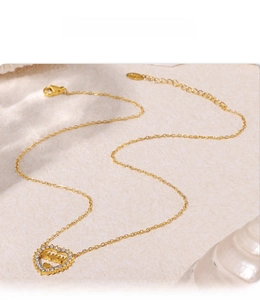 Macro shot of gold MAMA heart necklace with sparkling zircon pavé on beige texture