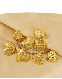 Detailed view of titanium steel heart earrings with textured gold finishes on silk
