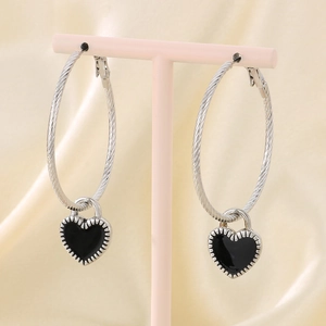 Detail of silver twisted rope hoop earrings featuring a black heart enamel pendant charm