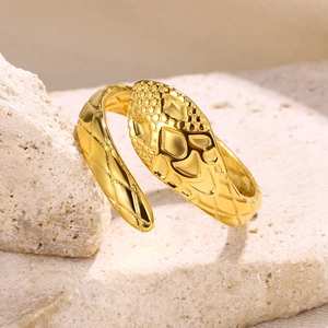 Macro shot of gold snake ring with detailed embossed scales on textured stone