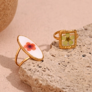 Detail of 18K gold hammered rings with oval red and square yellow dried flower resin