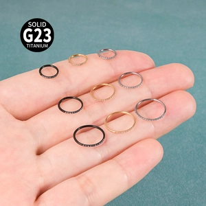 Macro shot of G23 titanium clicker rings with zircon in silver, gold and black