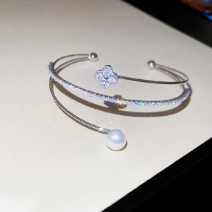Close-up of a silver-tone double-layer open bangle with zircon clover and a white pearl