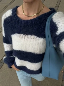 Detail of blue and white striped knit sweater featuring a soft crew neck wool blend texture