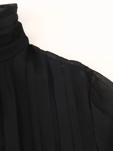 Detailed close-up of high-neck pleated chiffon dress with elegant shoulder stitching texture