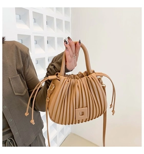 Detail of beige pleated bucket bag featuring vertical texture and drawstrings