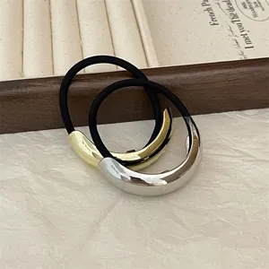 Close-up of minimalist gold and silver metallic curved charms on elastic hair ties