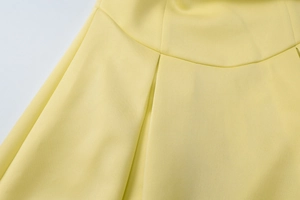 Dettaglio ravvicinato delle cuciture in vita e del design a pieghe di un abito estivo giallo