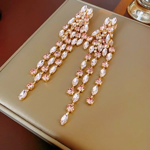 Close-up of tassel earrings with pink marquise crystals on a gold setting