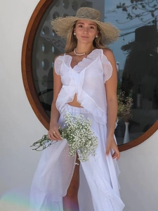 Detail of white ruffled chiffon crop top and high slit skirt for summer resort style