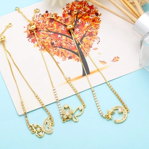 Detail of adjustable gold bracelets with pearl butterfly and moon charms with slider clasp