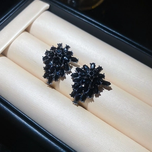 Macro detail of vintage floral earrings with black marquise crystals on beige velvet box