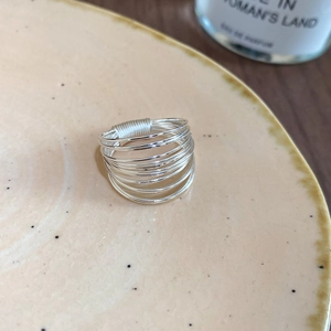 Detail of multi-layer silver star ring showing wire wrap design on ceramic dish