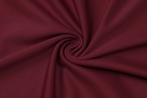 Makroaufnahme der dunkelroten Stricktextur und eleganten Spiralfalten am Kleid