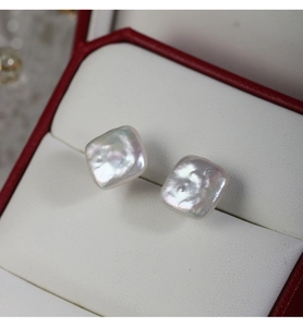 Macro shot of baroque square freshwater pearl earring on white cushion with soft lighting