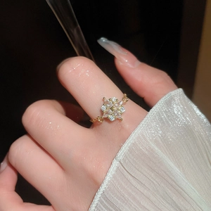 Detailansicht eines goldenen Blumenrings mit funkelnden Zirkonia an der Hand eines Models