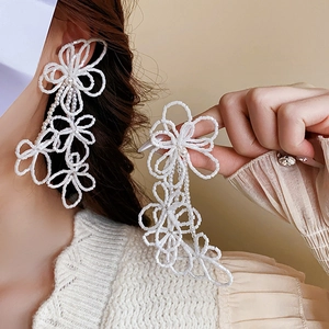 Close-up of elegant white seed bead flower tassel earrings with pearls on model