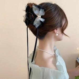 Elegant black ribbon bow hair claw with pearls and white butterfly on a female model