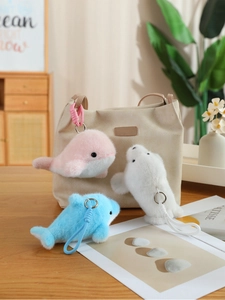 Close-up of plush dolphin and whale keychains in pink, white, and blue with braided ropes