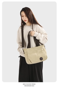 Canvas messenger bag with brown strap detail and front decorative label for women