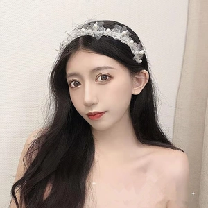 Detailed view of the crystal beaded headband with delicate white floral ornaments on a woman
