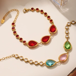 Detail of gold stainless steel anklets featuring vibrant red and multi-color crystal charms
