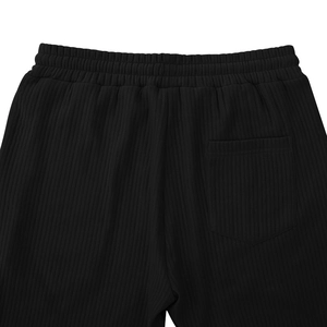 Detailed view of the elastic waistband and rear pocket on black ribbed trousers