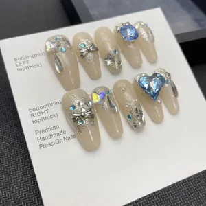 Handmade ballerina press-on nails with blue heart gems and silver bows on nude base