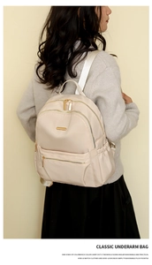 Side view of beige nylon backpack showing multi-pocket structure and side water bottle pouch