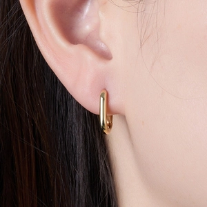 Macro shot of polished gold geometric oval earrings showing sleek minimalist metallic finish