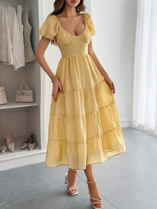 Vista dettagliata dell'abito midi giallo con maniche a sbuffo e gonna a balze sulla modella