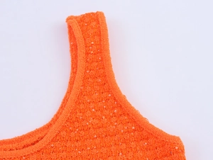 Makroaufnahme eines leuchtend orangefarbenen Pailletten-Stricktops mit Details