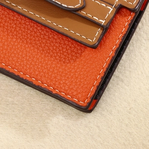 Close-up of orange litchi grain leather card holder with neat white stitching detail