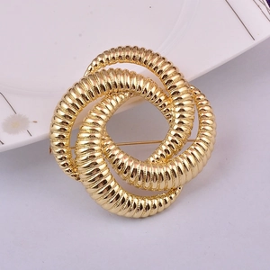 Elegante broche de metal en espiral dorado sobre plato blanco con luz suave