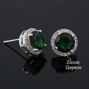 Macro detail of round halo stud earrings with deep green zircon and silver finish