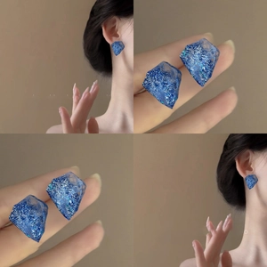 Close-up of blue irregular resin earrings with silver leaf inclusions and geometric cut