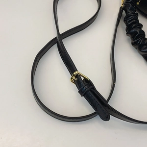 Close-up of adjustable black leather shoulder strap with gold buckle for crossbody bag