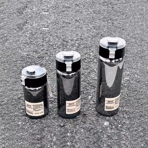 Three portable black water bottles in different sizes with lids on a gray outdoor surface