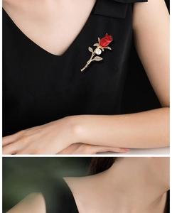 Detail of red rose brooch with crystals and pearl on a black elegant dress