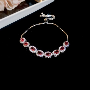 Détail macro d'un bracelet en argent avec sept pierres rouges ovales et halo de zircons