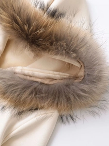 Detail shot of plush detachable faux fur collar on a cream hooded sweatshirt fabric
