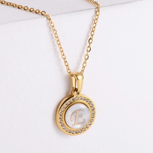 Detailed view of golden initial E pendant necklace with rhinestones and cat eye stone