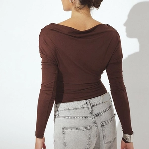 Detail of female model's back in slim-fit chocolate brown top with draped neck design